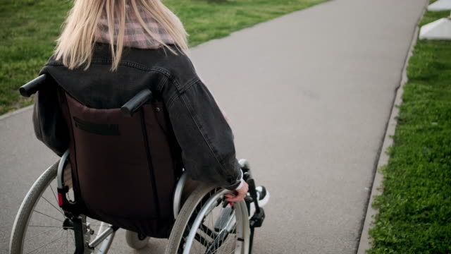 Mujer-discapacitada-se-mueve-en-carruaje-inválido-al-aire-libre,-primer-plano-del-cuerpo