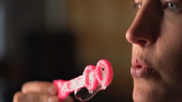 closeup-slow-motion-macro-lips-blowing-bubbles-from-pink-bubble-wand
