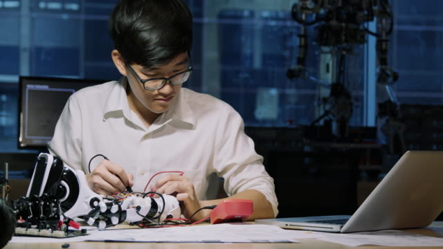 Asian-young-electronics-engineer-try-to-fix-robot-at-lab.-Technology-and-innovation-concept.