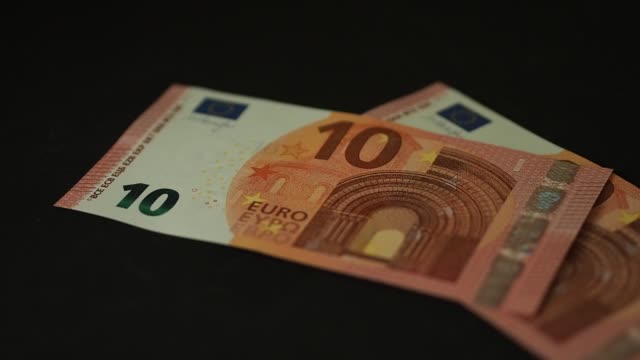 Banknoten-10-Euro-fallen-langsam-auf-den-schwarzen-Tisch.-Closeup.-zeitlupe