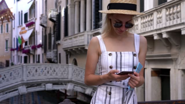 Positive-Millennial-weibliche-Tourist-schreiben-E-Mail-über-mobile-Anwendung,-während-auf-dem-Showplatz-ruhen-und-mit-öffentlichen-Internetverbindung