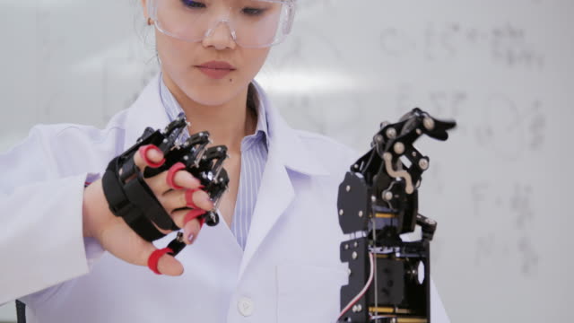 Mujer-asiática-probando-cyborg-mano-en-el-laboratorio.