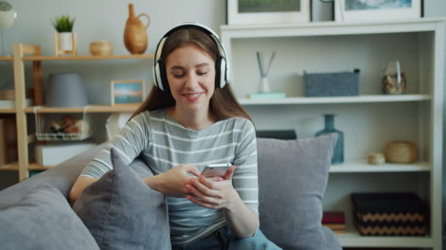 Schöne-junge-Frau-hört-Musik-mit-Kopfhörern-mit-dem-Smartphone