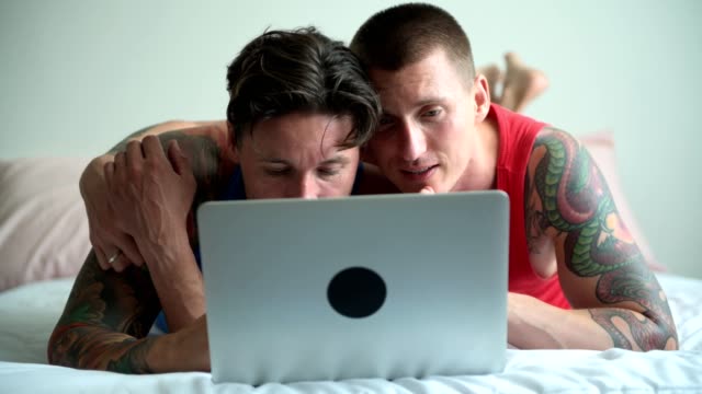 Schwules-Paar-im-Bett-mit-Laptop-Computer.-Konzentrieren-Sie-sich-auf-den-Computer.
