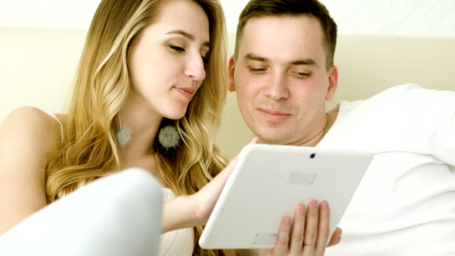 Feliz-pareja-viendo-una-película-divertida-en-la-tableta-de-la-computadora-juntos-en-el-dormitorio.-4K