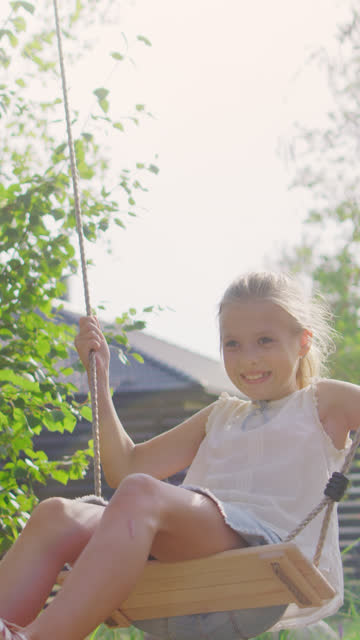 Joyous-Father-Pushes-Swings-with-His-Cute-Little-Daughter-on-Them.-Happy-Family-Spends-Time-Together-one-Sunny-Summer-Day-in-the-Idyllics-Backyard.-Video-Footage-with-Vertical-Screen-Orientation