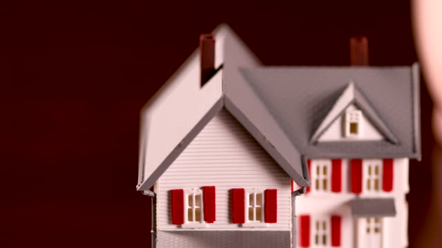 Pan-of-Piggy-Bank-and-Miniature-House-on-Dark-Wood-Surface
