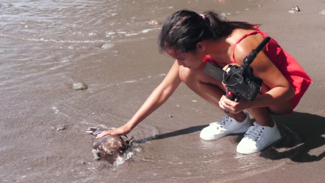Una-vlogger-hembra-encontró-un-pez-muerto-en-la-orilla-del-mar-al-filmar-video.