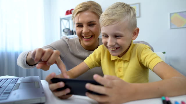 Mother-and-little-son-playing-together-new-game-on-smartphone,-leisure-time,-app