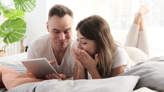 Couple-using-digital-tablet-in-bed
