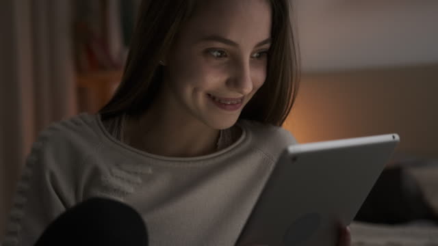Teen-Mädchen-genießen-Medieninhalte-auf-digitalen-Tablet-in-der-Nacht