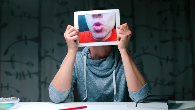 Ein-Mann-hält-eine-Tablette-in-den-Händen,-auf-dem-Tablet-Bildschirm-eine-Nahaufnahme-seiner-Lippen