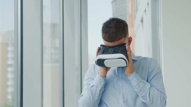 Nahaufnahme-Junger-Mann,-der-an-einem-Schreibtisch-im-Büro-sitzt,-verwendet-Augmented-Reality-Brillen,-um-an-Geschäftsprojekten-in-verschiedenen-Bereichen-zu-arbeiten.-Arbeiten-in-Virtual-Reality