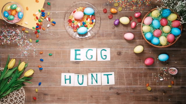 Man-puts-words-Egg-hunt-on-table-decorated-with-easter-eggs.-Top-view