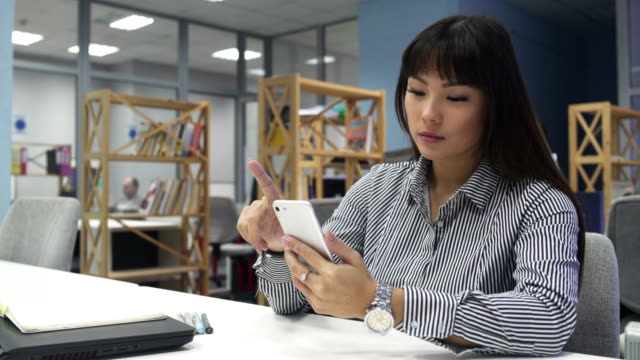 Mujer-joven-con-plata-Smartphone-en-la-oficina