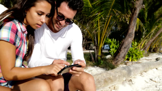Couple-Taking-Selfie-On-Cell-Smart-Phone-Outdoors-Under-Palm-Trees,-Happy-Smiling-Man-And-Woman-Watching-Photo