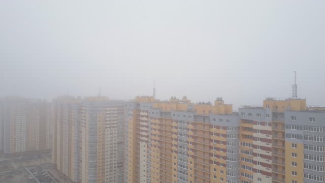 Aerial-view.-Residential-high-rise-buildings-in-the-city-in-the-fog.-New-yellow-houses-with-residential-apartments.-Builders-build-many-new-houses-in-big-cities-for-sale-and-rent-of-real-estate