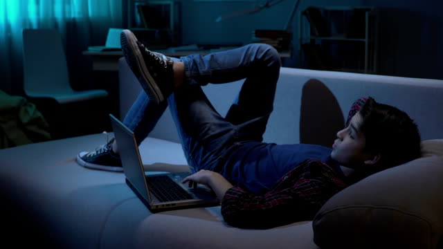 Estudiante-masculino-de-relajarse-en-el-sofá-con-el-portátil,-mirar-imágenes-en-la-red-social