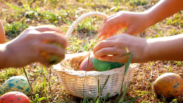 Nahaufnahme-von-zwei-Kindern-nehmen-Ostern-Eiern-in-Korb-im-Sonnenschein-Hintergrund