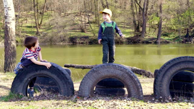 Two-kids-playing-together-jumping-and-climbing-on-old-tires