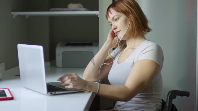 Glückliche-Frau-Musikhören-und-tippen-auf-Laptop