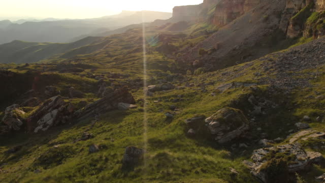 Ein-Blick-von-oben-auf-ein-Tal,-gesäumt-von-großen-Steinen-am-Fuße-einer-hohen-Klippe.-Ein-Sonnenuntergang-Panorama-des-Kaukasus-mit-einer-Umdrehung.-Überprüfung-der-epischen-Ort-in-4-k-100-Mbit/s