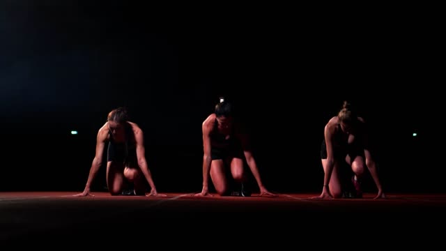 Drei-Mädchen-in-schwarzen-Klamotten-sind-in-der-Start-Pads-zum-start-des-Rennens-am-Wettbewerb-im-Licht-der-Laternen