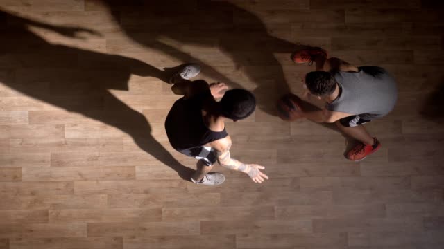 TopShot,-dos-jugadores-de-baloncesto-uno-frente-al-otro-en-cancha-y-tratando-de-sacar-bola