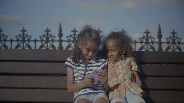 Kinder-im-Chat-online-mit-Smartphone-auf-Bank