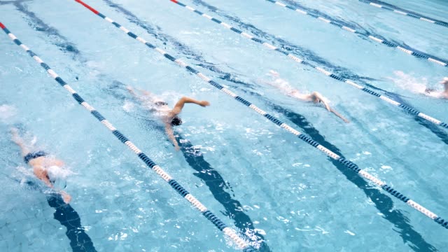 Vista-superior-cuatro-nadador-profesional-flotando-en-pista-en-piscina-realizar-estilo-crol