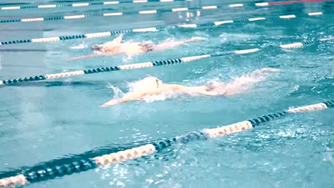High-angle-three-swimmers-having-competition-in-swimming-pool-tracking-shot