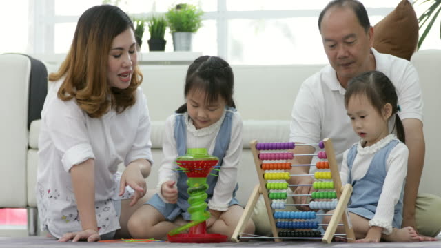 Feliz-familia-asiática-con-dos-hijas,-jugando-en-casa.-Familia-sentada-en-el-piso-y-jugar-juntos.