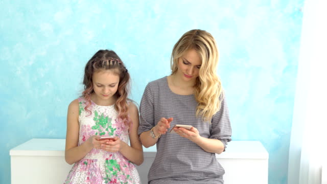 Mutter-und-Tochter-suchen-in-ihren-Handys-nebeneinander-sitzen-und-reden-nicht.