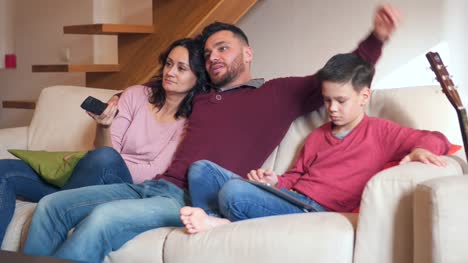 Familie-vor-dem-Fernseher-und-mit-digital-Tablette-zu-Hause
