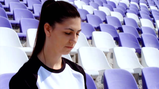 Young-woman-footballer-seating-with-football-soccer-ball-on-stadium,-4k