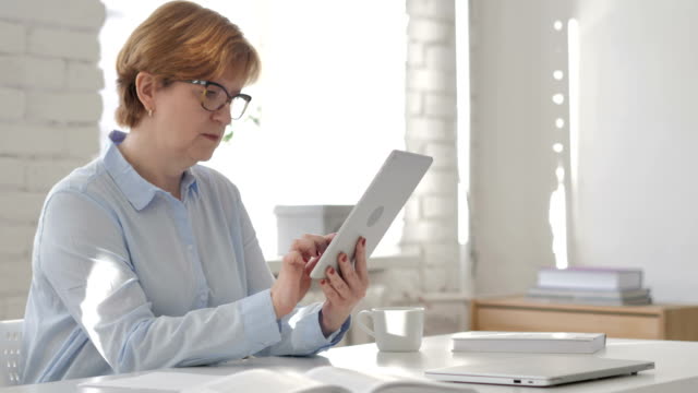 Old-Woman-Using-Tablet-at-Workplace