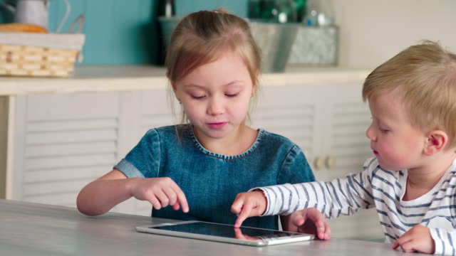Niños-caucásicos-usando-tableta-juntos-en-casa