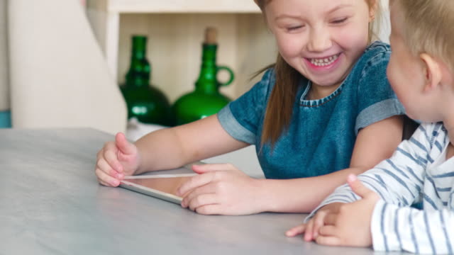 Kinder-lachen-und-spielen-auf-Tablet-zusammen-zu-Hause