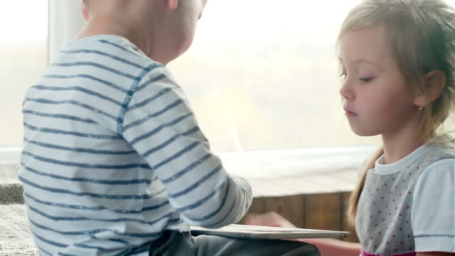 Kleiner-Junge-und-seine-Schwester-spielen-auf-Tablet