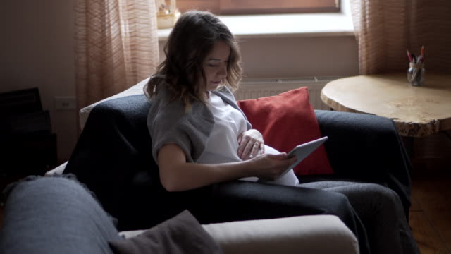 Pregnant-woman-watching-media-content-on-digital-tablet