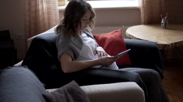 Schwangere-Frau-gerade-Medieninhalte-auf-digital-Tablette