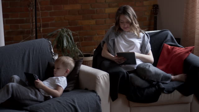 Pregnant-mother-and-son-using-digital-tablet-at-home