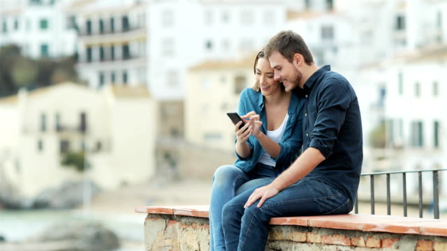 Couple-browsing-on-phone-on-a-ledge