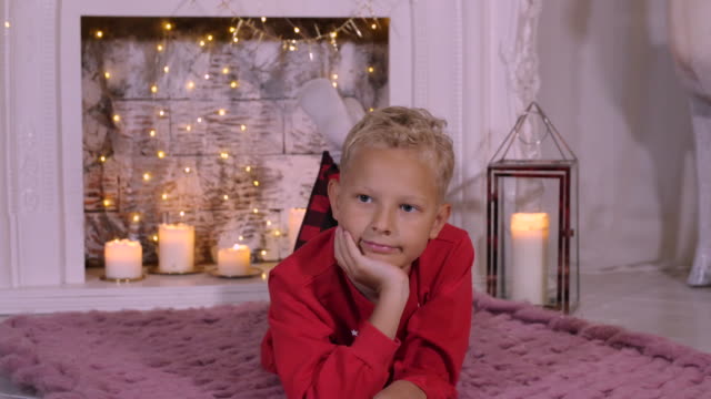 Portrait-teenager-boy-lying-on-cozy-carpet-on-Christmas-fireplace-background