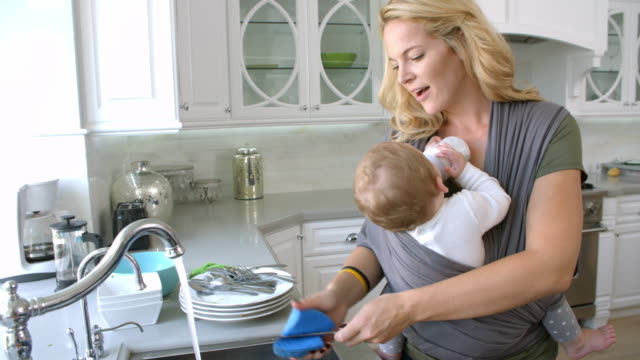 Busy-Mother-With-Baby-In-Sling-At-Home,-Slow-Motion
