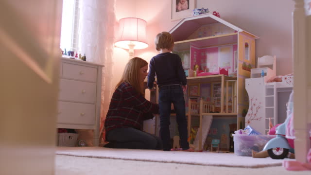 Ein-kleines-Mädchen-und-ihre-Mutter-mit-einem-riesigen-Puppenhaus-in-ihrem-Zimmer-spielen