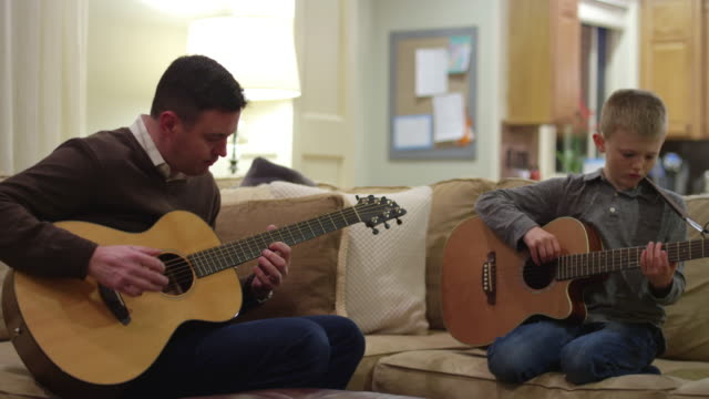 Vater-und-Sohn-üben-auf-ihren-Gitarren-im-Wohnzimmer
