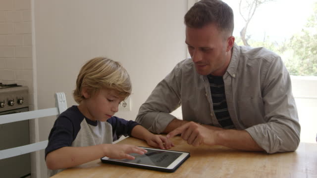 Vater-und-Sohn-mit-Tablet-Computer-am-Küchentisch,-auf-R3D-geschossen
