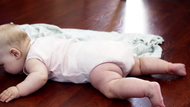 Adorable-little-baby-lie-on-floor-on-stomach.-Apartment.-Cute-movements