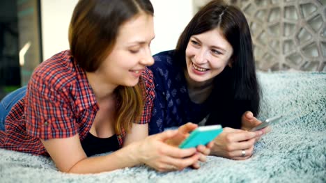 Zwei-glückliche-Frauen-Freunde-teilen-von-sozialen-Medien-in-ein-smart-Phone-und-reden